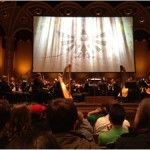 The orchestra awaits the conductor to begin the Symphony